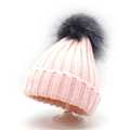 Close-up of knit texture and gray faux fur pom-pom on a pink winter knit beanie - Pink