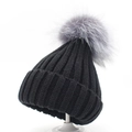 Detail of thick ribbed knit winter beanie in black with a large grey faux fur pom pom - Kids / Black