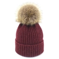 Détail d'un bonnet en maille bordeaux avec un pompon duveteux en fausse fourrure marron - Bordeaux