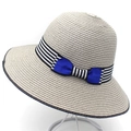 Close-up of woven straw sun hat with striped ribbon and blue bow detail on white stand - Gray