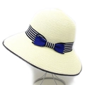 Detail of summer straw hat featuring black and white striped ribbon and dark blue bow - Cream