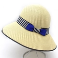 Detail of summer straw hat with black white striped band and vibrant blue double bow - Beige