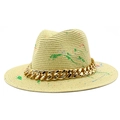 Detail view of straw fedora hat featuring colorful paint splatters and gold chain link - Beige
