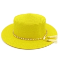 Detail of yellow straw boater hat featuring gold chain, faux pearls, and tassel charms - Yellow