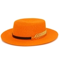 Detailed macro view of vibrant orange straw boater hat with black band and gold leaf - Orange