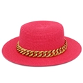 Gros plan d'un chapeau de paille fuchsia orné d'une chaîne dorée épaisse et élégante - Rose rouge