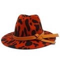 Detail view of the orange cow print fedora hat featuring a brown leather decorative band - One Size / Brick Red Leopard