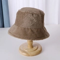 Close-up detail of plush brown bucket hat showing soft faux fur texture on a wooden stand - Light Brown