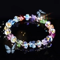 Buntes Glasperlenarmband mit Kristall-Schmetterlingen und goldenen Akzenten auf dunklem Grund - bunt