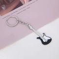 Macro view of a mini electric guitar keychain in black and white finish on a magazine - Black Guitar Keychain
