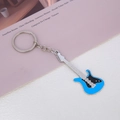 Close-up of blue electric guitar keychain with metal enamel finish on pink background - Blue Guitar Keychain