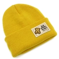 Détail d'un bonnet en tricot jaune vif avec un écusson blanc orné d'un petit ours brun - Jaune