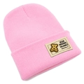 Détail d'un bonnet en maille rose avec un écusson d'ours rectangulaire et étiquette - Rose