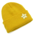 Close-up of yellow knitted beanie featuring a star embroidery with a black smiley face - Yellow