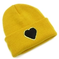 Close-up of yellow knit beanie featuring a black heart patch with gold glitter edges - Yellow