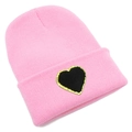 Detailed view of pink knitted beanie featuring a black heart patch with golden glitter edges - Pink