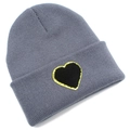 Close-up of gray knit beanie featuring a black heart patch with gold glitter edges - Gray