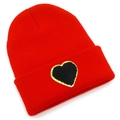 Close-up of red knit beanie featuring a black heart patch with gold sequin border - Red