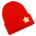 Close-up detail of a red knitted beanie with a golden star smile embroidery patch - Red
