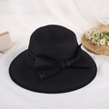 Detail shot of black wide brim straw hat with elegant bow and metallic M emblem - Black