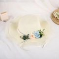 Dettaglio cappello di paglia estivo con tesa ondulata e decorazioni floreali eleganti - Beige