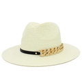 Détail d'un chapeau de paille beige avec bande en cuir noir et chaîne gourmette dorée texturée - Crème