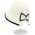 Cream knit bucket hat with black contrast trim and large rhinestone bow on a stand - White