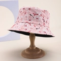 Pink floral bucket hat with cherry blossom pattern and black inner lining on wooden stand - Pink Base White Sakura (81)
