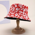 Dettaglio di un cappello da pescatore rosso con motivi floreali su supporto in legno - Rosso