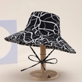 Close-up of black and white abstract print cotton bucket hat with adjustable bow tie strap - Black White Abstract Line Style (22#)