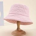 Light pink puffer bucket hat with heart quilted patterns on a wooden display stand - Pink
