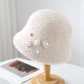 Detail of cream plush bucket hat featuring cute teddy bear and heart embellishments - One Size / Beige