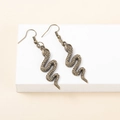 Detailed macro view of vintage bronze snake-shaped earrings showing fine scale textures - Bronze