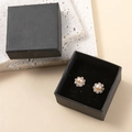 Macro-opname van lichtoranje pareloorbellen in bloemvorm in een luxe zwarte doos - Lichtroze Parel Strass Bloem Stijl
