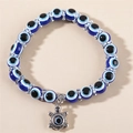 Nahaufnahme eines blauen Evil Eye Perlenarmbands mit einem silbernen Schildkrötenanhänger - Blaue Schildkröte