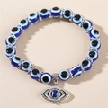 Bracelet en perles de résine Evil Eye bleu avec pendentif argenté sur beige - Grand Œil Bleu