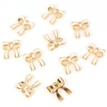 Detailed macro view of ten white enamel bow alloy charms with golden metal edges - Bow / White