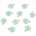 Close-up of light blue enamel flower charms with gold edges and loops for jewelry making - Flower / Blue