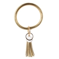 Detail eines goldenen Lederarmband-Schlüsselanhängers mit weißen Scheiben und Fransenquaste - Goldgelb