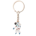 Detail of golden astronaut keychain with white enamel finish and vibrant blue accents - Astronaut