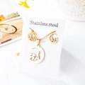 Macro detail of golden stainless steel jewelry set featuring Eiffel Tower silhouette - Crescent Moon Eiffel Tower Style