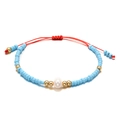 Detail van blauwe kralenarmband met gouden accenten en een witte zoetwaterparel in het midden - Lichtblauw