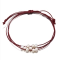 Detailopname van de handgemaakte rode gevlochten armband met natuurlijke zoetwaterparels - Bordeauxrood