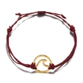 Detail of red woven beach bracelet with a golden circular wave charm in minimalist style - Bright Red