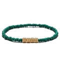Dettaglio ravvicinato di un bracciale di perline verdi con quattro cubi in metallo oro - Smeraldo