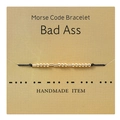 Detail of handmade gold Morse code bracelet on textured gift card with letter coding - Bad Ass