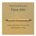 Detail of Morse code bracelet with gold beads and black cord on kraft card - face shit
