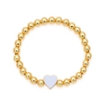Dettaglio di un bracciale a sfere dorate con ciondolo a cuore lilla e bordo in oro - Bianco
