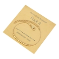 Detail showing golden morse code bracelet with beads and tubes on brown display card - Fuck It Theme