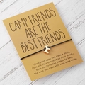 Detailaufnahme des Wunscharmbands mit Pfotenanhänger auf einer Camp Friends Karte - Schwarzes Seil